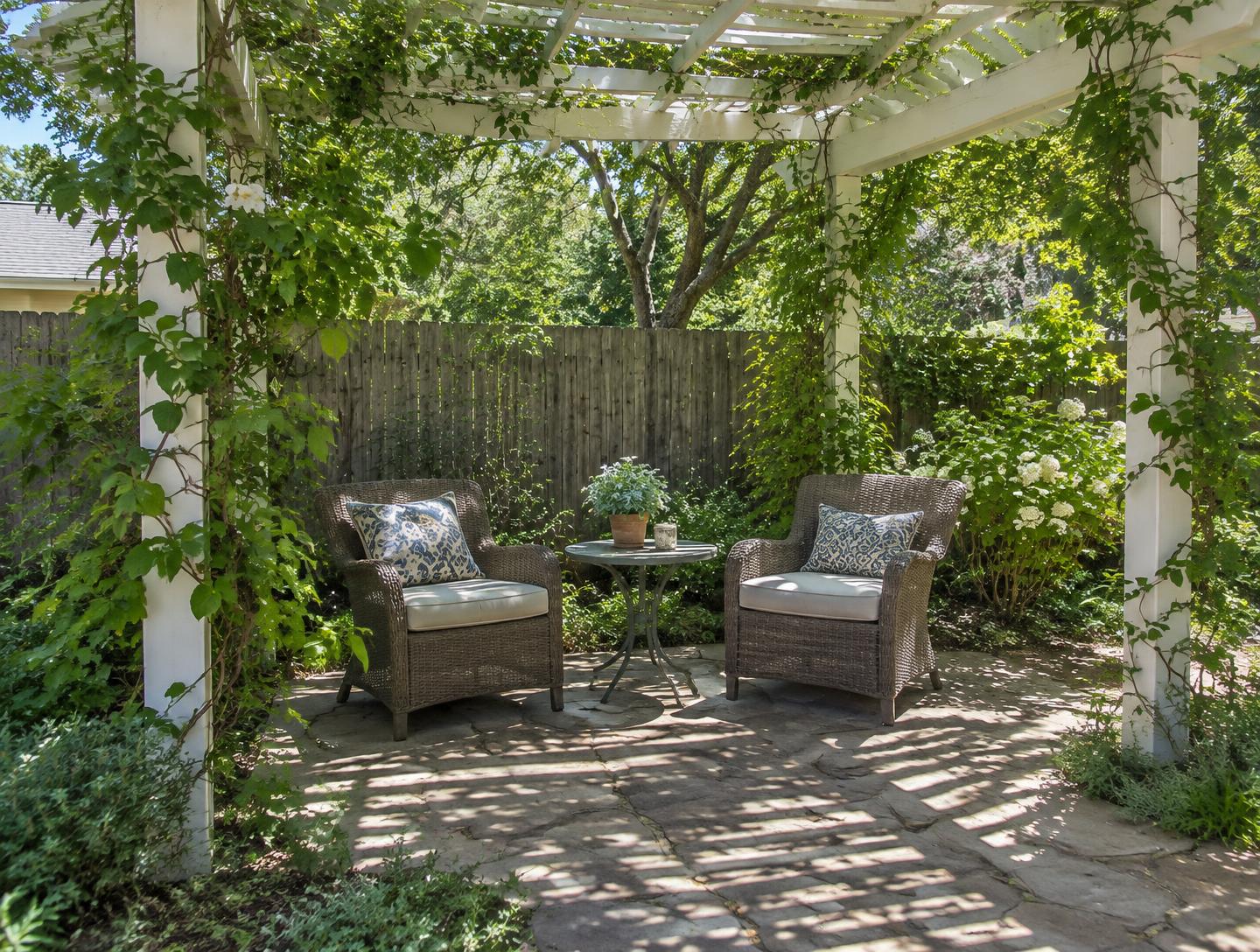 White garden pergola with climbing plants shading a small seating area